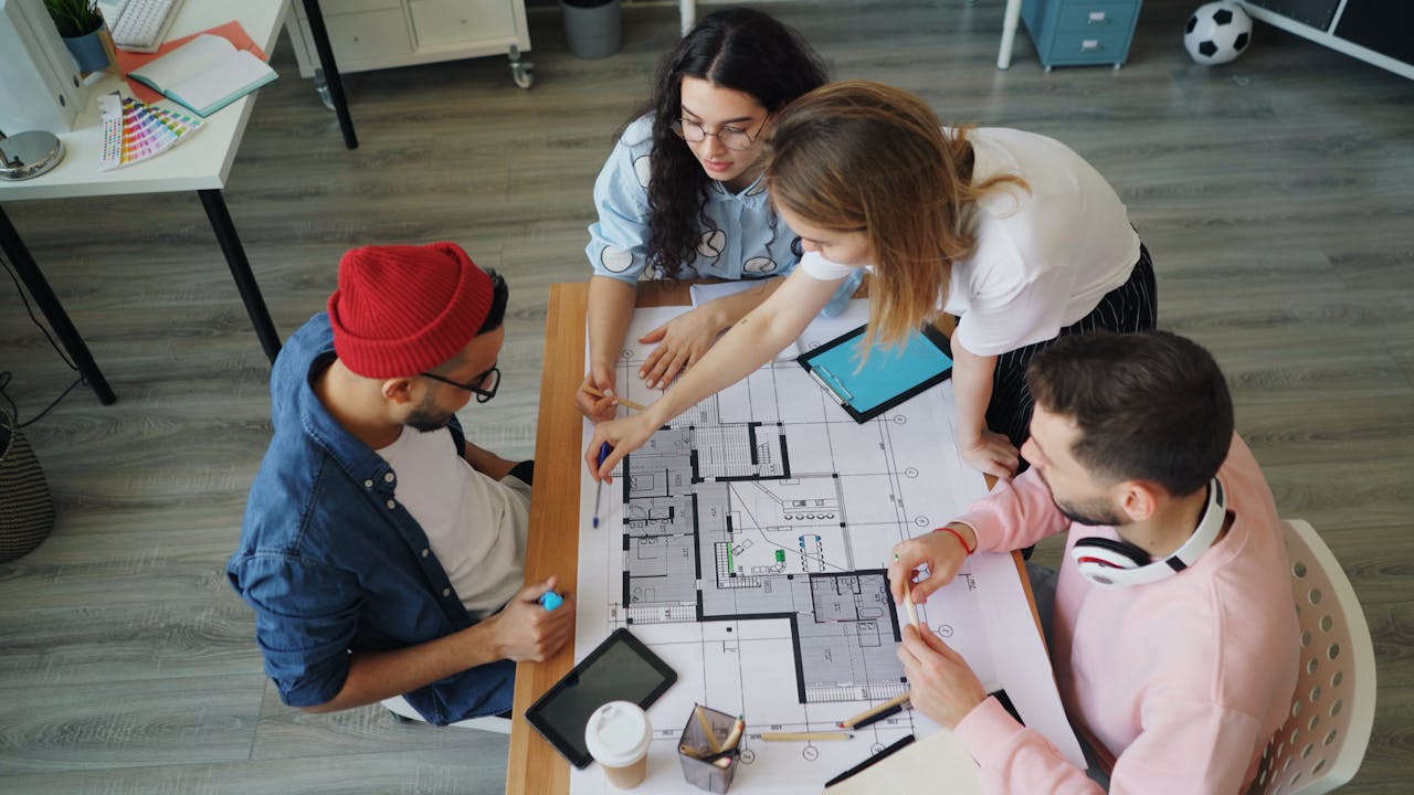 Mastering the First Impression: Your intriguing post title goes here Young creative professionals discussing an architectural blueprint in a modern office setting.