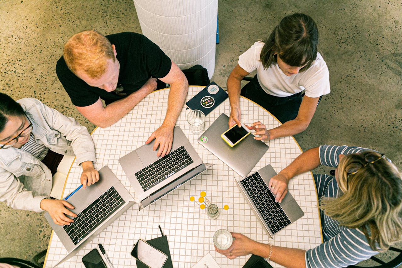 services-02 Top view of team collaborating in a modern office around laptops, discussing ideas.